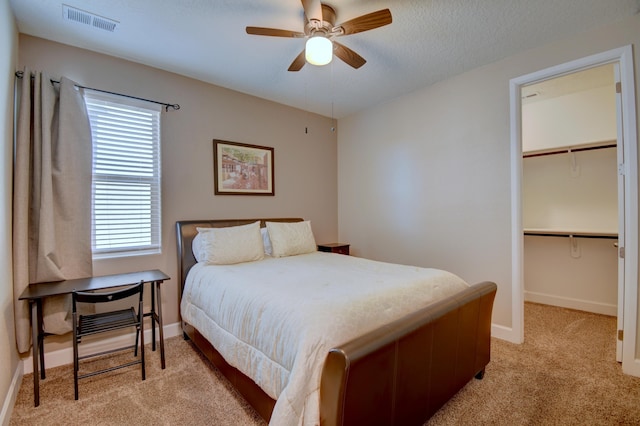 carpeted bedroom featuring ceiling fan, a spacious closet, a textured ceiling, and a closet