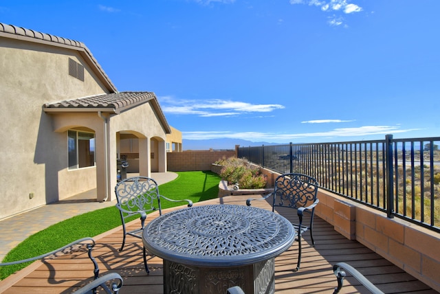 deck with a lawn, a mountain view, and a patio area