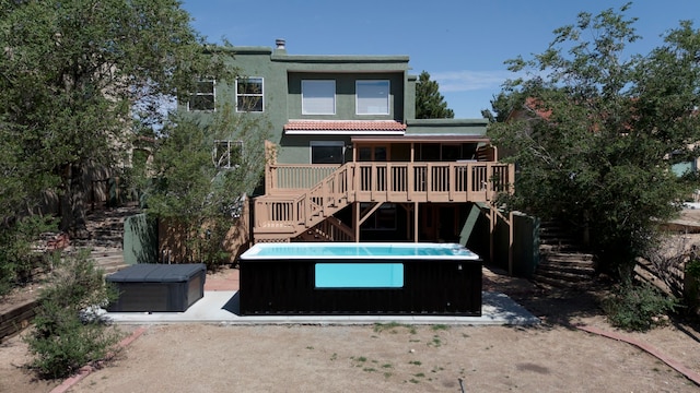 back of property featuring a hot tub and a wooden deck