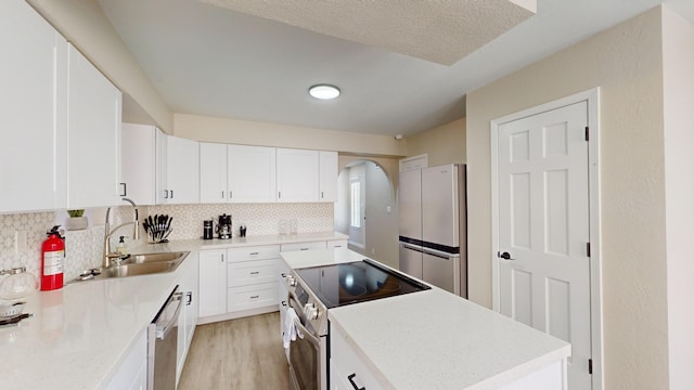 kitchen with sink, light hardwood / wood-style flooring, backsplash, white cabinets, and appliances with stainless steel finishes