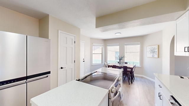 kitchen with white cabinets, electric range, a textured ceiling, dishwashing machine, and light hardwood / wood-style floors