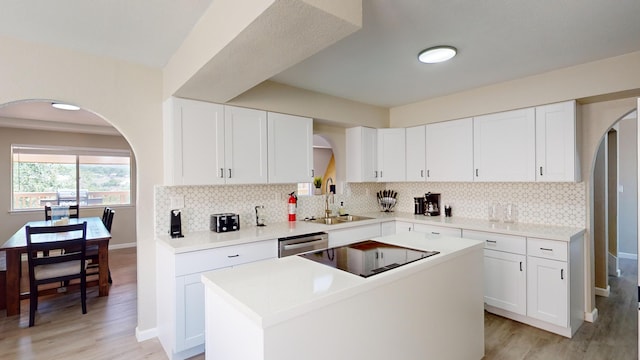 kitchen with backsplash, a kitchen island, white cabinetry, and sink