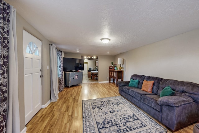 living room with a textured ceiling, wood finished floors, and baseboards