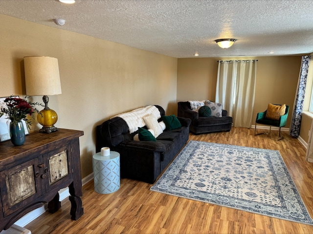 living room featuring baseboards, a textured ceiling, and light wood finished floors