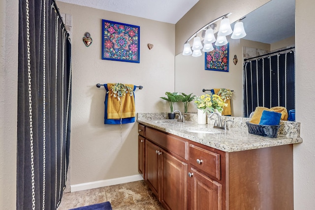 bathroom featuring a sink, baseboards, and double vanity