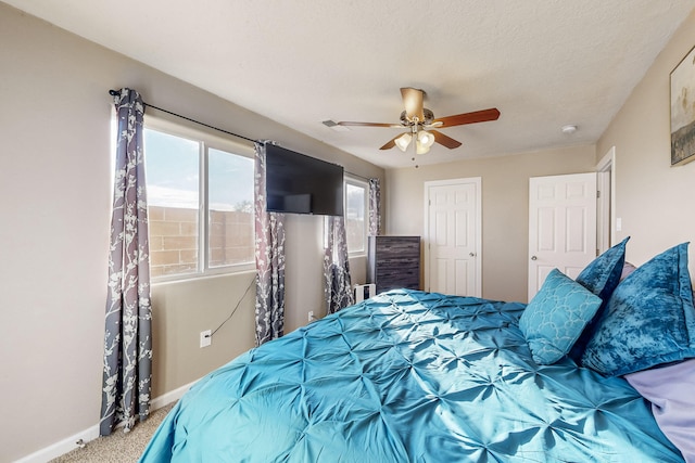 bedroom featuring a ceiling fan, carpet flooring, a textured ceiling, and baseboards