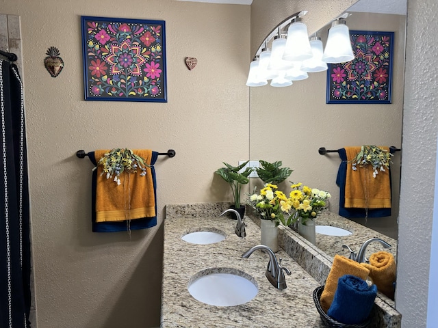 full bathroom featuring double vanity, a sink, and a textured wall