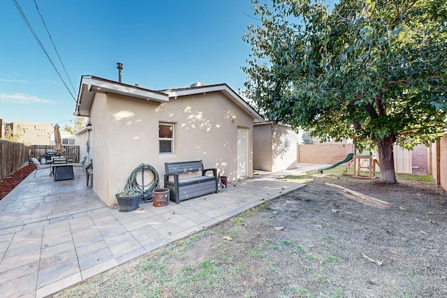 rear view of property featuring a fenced backyard, a playground, and stucco siding