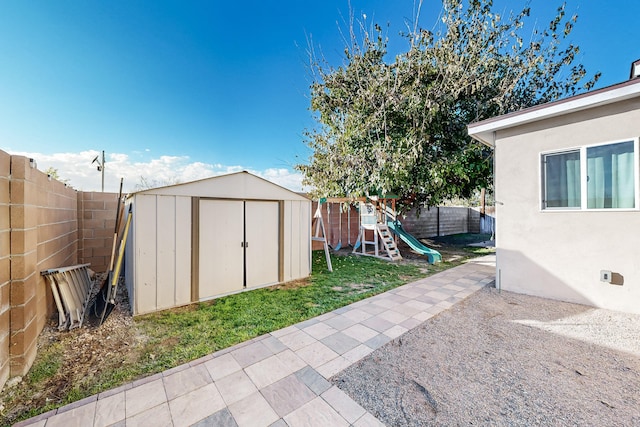 view of yard with an outbuilding, a playground, a fenced backyard, a shed, and a patio area