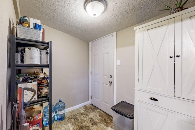 doorway featuring a textured ceiling and baseboards