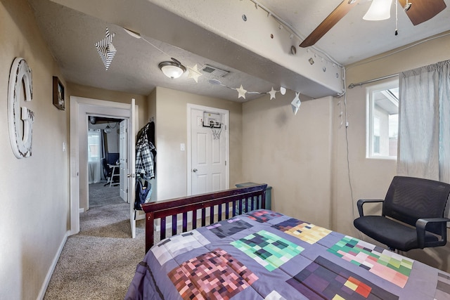 carpeted bedroom with visible vents, baseboards, and ceiling fan