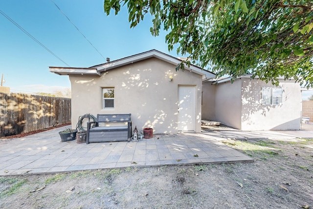 view of side of home featuring a patio area, a hot tub, fence, and stucco siding