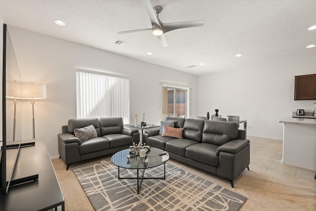 tiled living room with ceiling fan and a textured ceiling