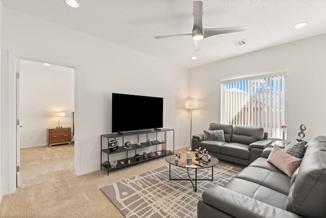 living room with ceiling fan, light colored carpet, and a textured ceiling