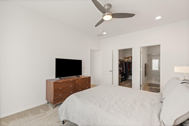 carpeted bedroom with a closet, a walk in closet, ensuite bathroom, and ceiling fan