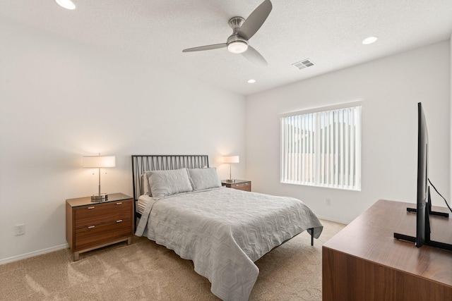 carpeted bedroom featuring ceiling fan and a textured ceiling