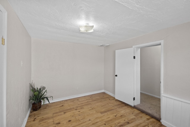 empty room featuring a textured ceiling and light hardwood / wood-style flooring