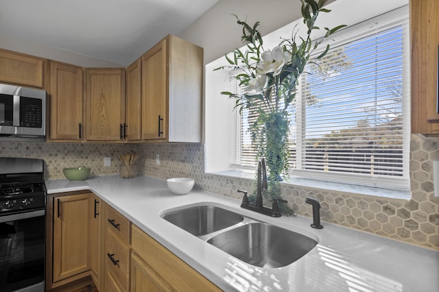 kitchen with decorative backsplash, black range with gas stovetop, and sink