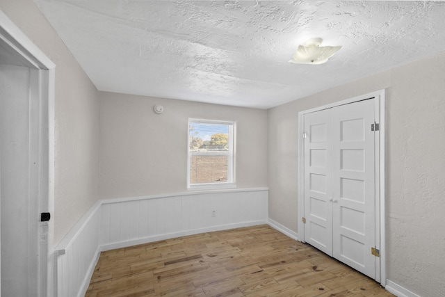 unfurnished room featuring a textured ceiling and light hardwood / wood-style flooring