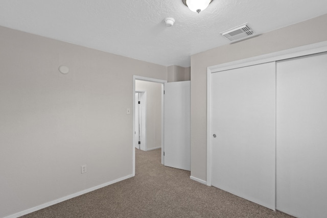 unfurnished bedroom with light carpet, a closet, and a textured ceiling