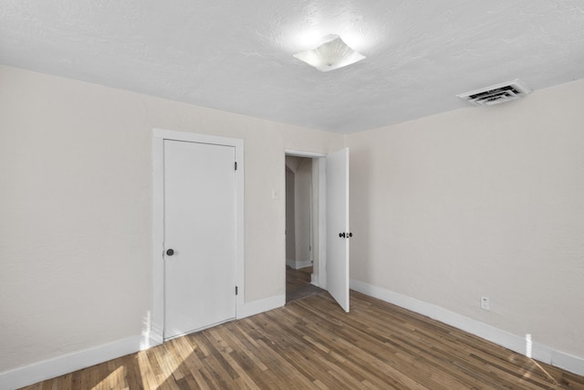 unfurnished bedroom featuring wood-type flooring, a textured ceiling, and a closet