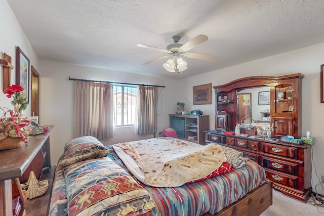 carpeted bedroom featuring ceiling fan and a textured ceiling