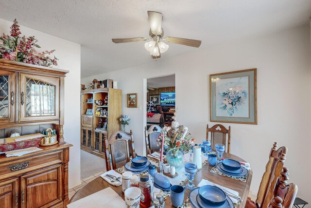 carpeted dining space with ceiling fan and a textured ceiling