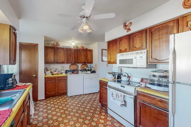 kitchen featuring separate washer and dryer, ceiling fan, sink, and white appliances