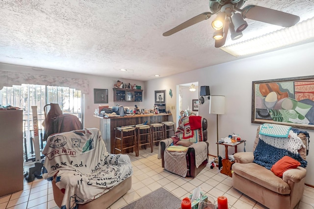 tiled living room featuring ceiling fan, a textured ceiling, and bar area