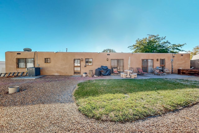 back of property with a lawn, a patio area, and central AC