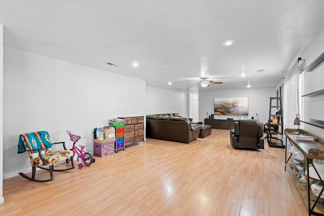 living room featuring ceiling fan, a textured ceiling, and hardwood / wood-style flooring