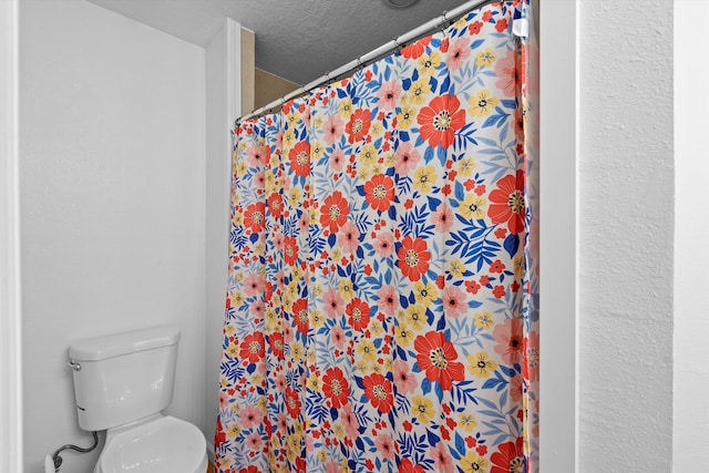 bathroom with a shower with shower curtain, toilet, and a textured ceiling