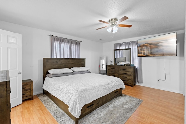 bedroom with ceiling fan, hardwood / wood-style floors, and a textured ceiling