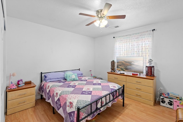 bedroom with ceiling fan, a textured ceiling, and light hardwood / wood-style flooring