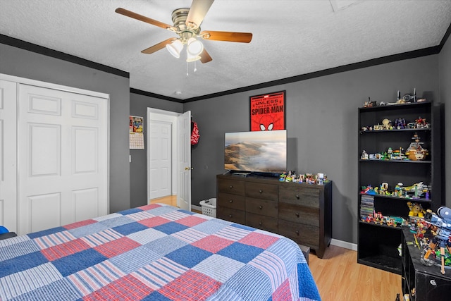 bedroom with ceiling fan, crown molding, a textured ceiling, a closet, and light wood-type flooring