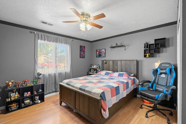 bedroom with a textured ceiling, hardwood / wood-style flooring, ceiling fan, and crown molding