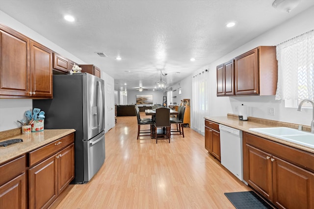 kitchen with stainless steel fridge, light wood-type flooring, a textured ceiling, sink, and dishwasher