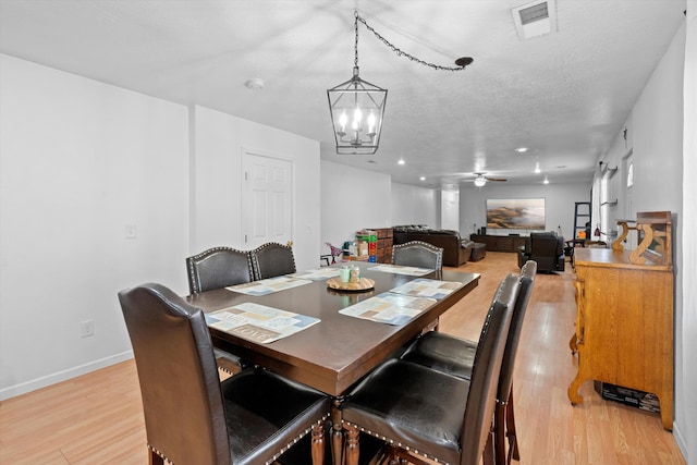 dining area featuring ceiling fan with notable chandelier, light hardwood / wood-style floors, and a textured ceiling