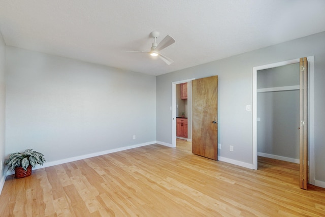 unfurnished bedroom featuring light hardwood / wood-style floors, ceiling fan, and multiple closets