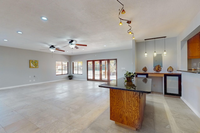 kitchen featuring pendant lighting, a textured ceiling, a kitchen island, and ceiling fan