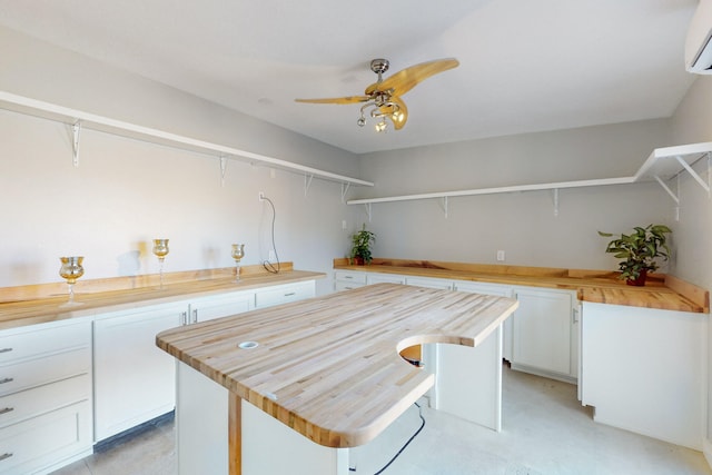 kitchen with wood counters, a center island, white cabinets, ceiling fan, and a wall unit AC