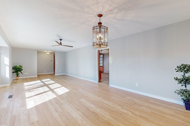 spare room featuring light hardwood / wood-style floors and ceiling fan with notable chandelier