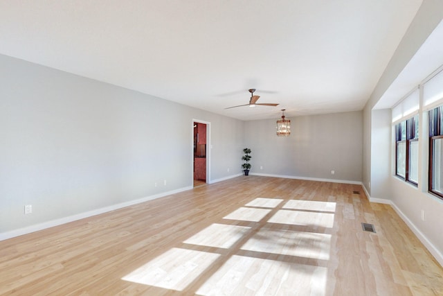 empty room featuring light hardwood / wood-style floors and ceiling fan with notable chandelier