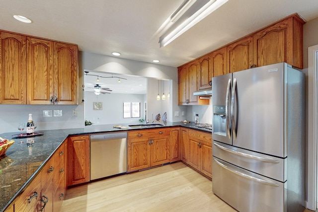 kitchen with stainless steel appliances, ceiling fan, sink, light hardwood / wood-style flooring, and hanging light fixtures