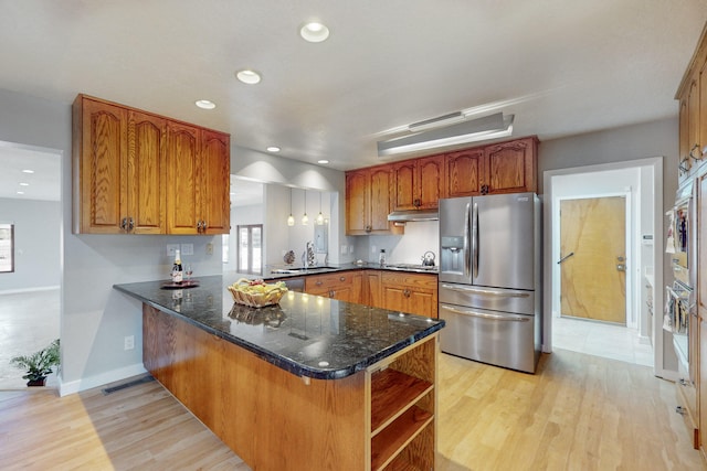 kitchen with light hardwood / wood-style floors, dark stone countertops, kitchen peninsula, and stainless steel appliances