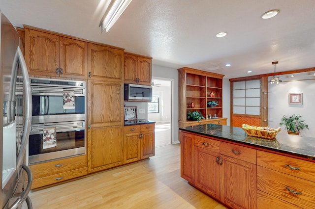 kitchen with light hardwood / wood-style flooring, dark stone countertops, pendant lighting, a textured ceiling, and appliances with stainless steel finishes