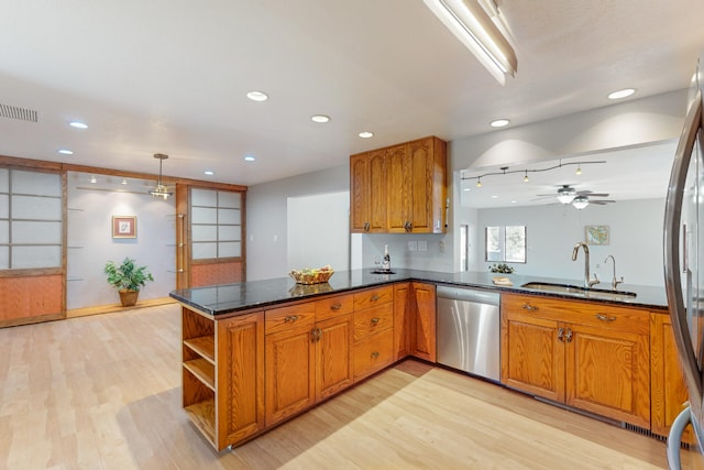 kitchen with hanging light fixtures, sink, light wood-type flooring, kitchen peninsula, and stainless steel appliances