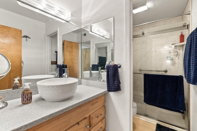 bathroom with hardwood / wood-style floors, vanity, an enclosed shower, and toilet