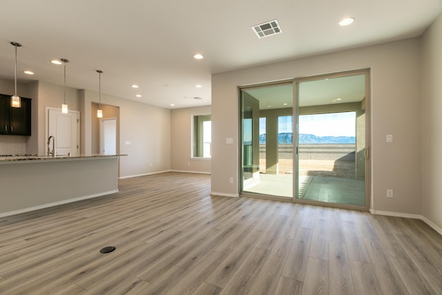 unfurnished living room with a mountain view, sink, and hardwood / wood-style flooring