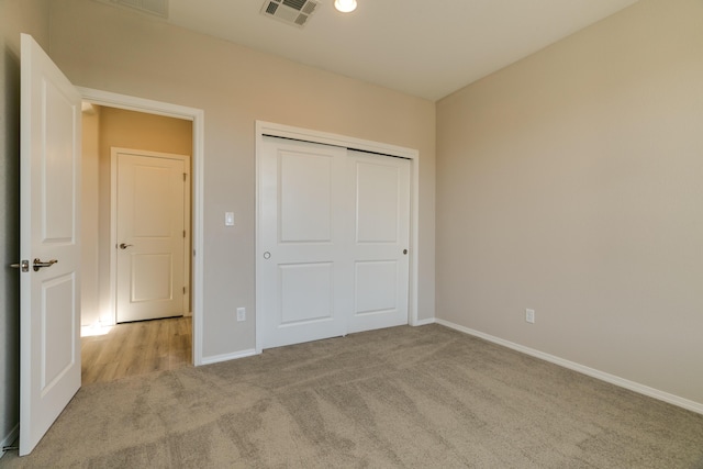 unfurnished bedroom featuring light carpet and a closet